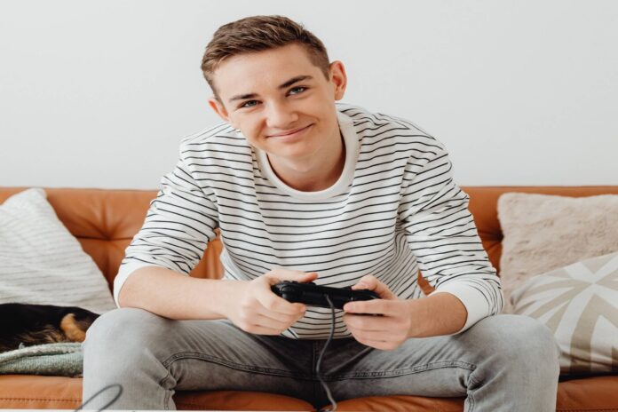 Ragazzo seduto sul divano con un controller per videogiochi, immagine di repertorio