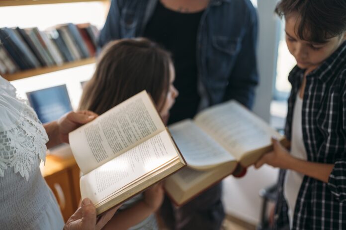 Gruppo di persone che legge libri insieme in biblioteca