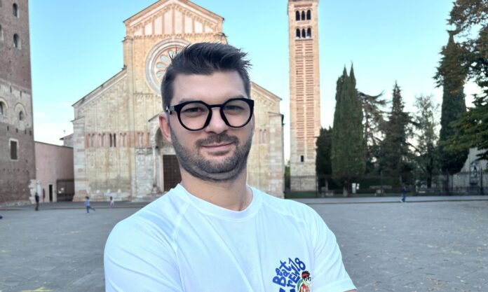 Enrico Aldrighetti davanti alla basilica di San Zeno a Verona, con la maglietta BeatCrew18