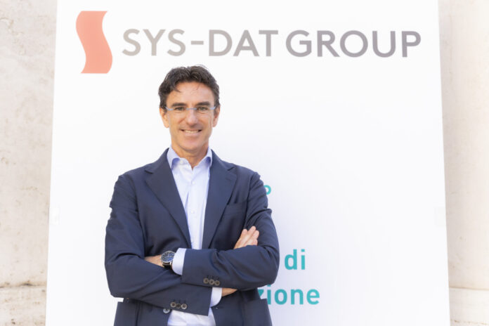 Matteo Neuroni, CEO di SYS-DAT Group, davanti al marchio della società
